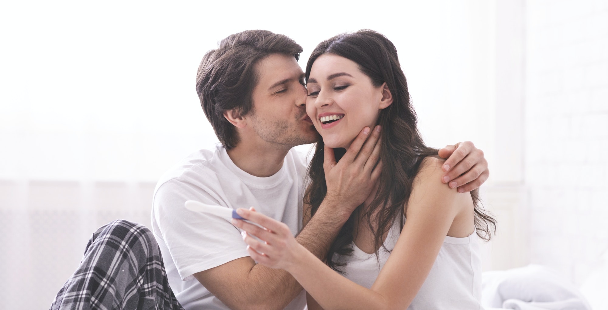 Enamoured couple finding out positive results of pregnancy test